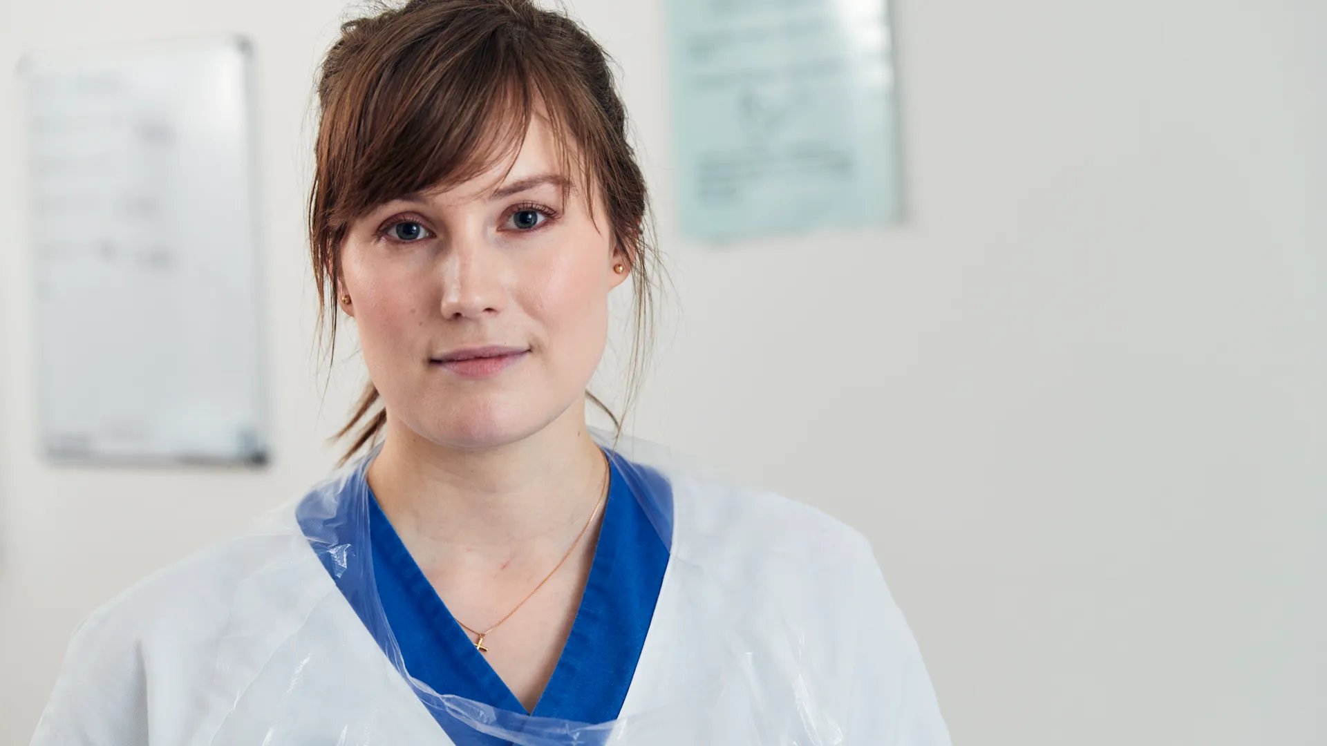 En kvinna i vit labbrock med ett blått band runt halsen.